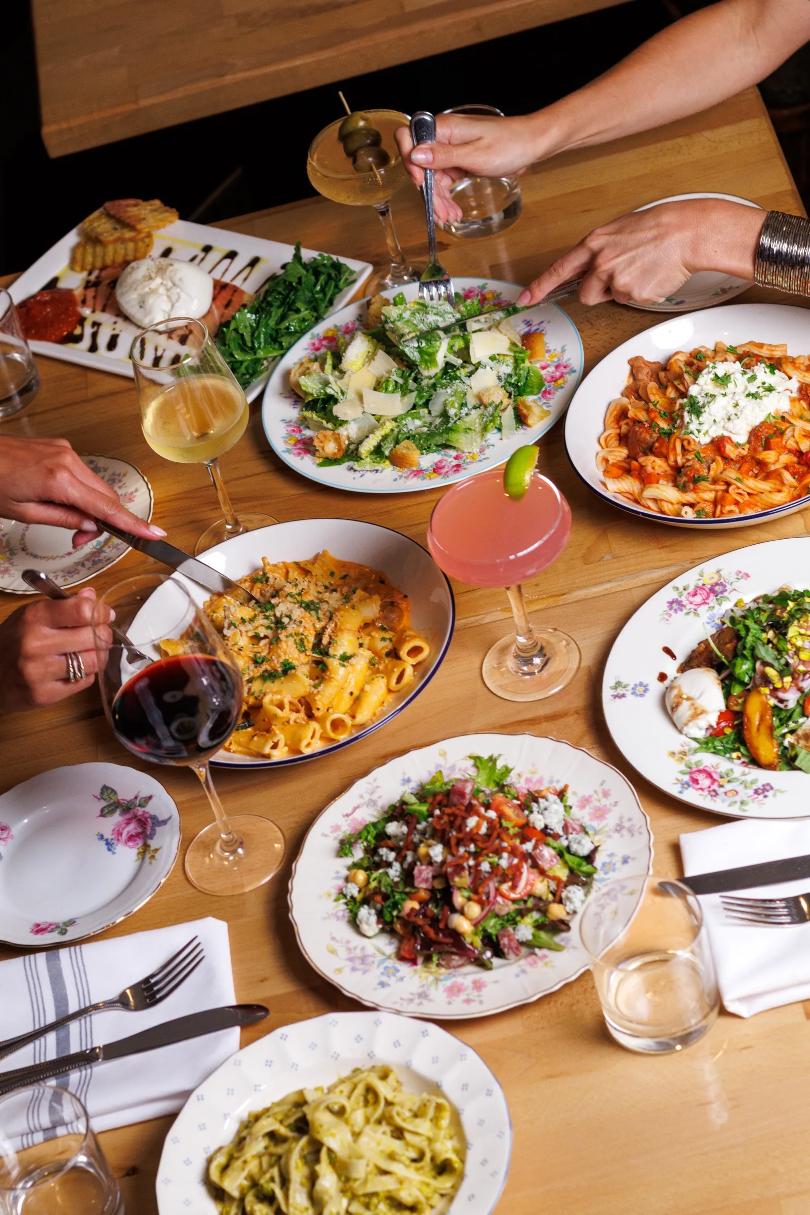 A shared table of pasta, salads, and cocktails at Osteria Danny